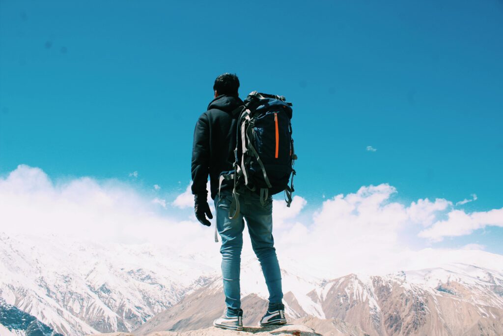 pexels-photo-2577274-2577274 A lone hiker with a backpack surveys snow-capped mountains under a clear blue sky.